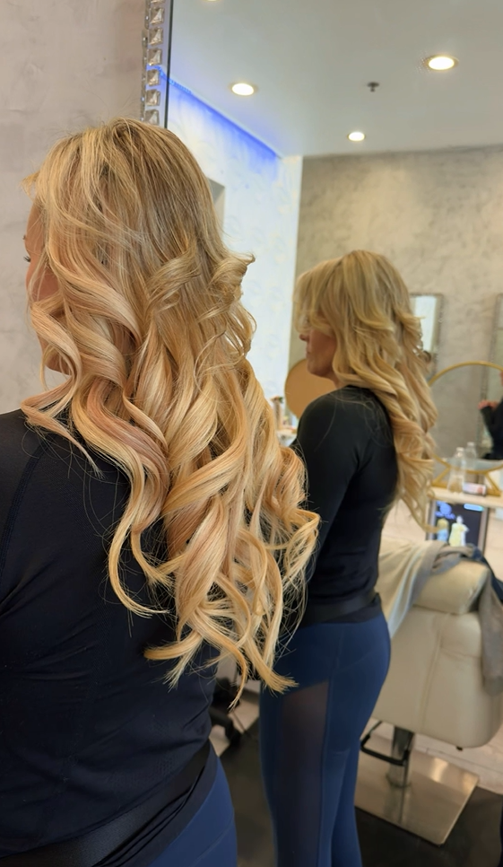 Cascading blonde curls styled at Roza Glam